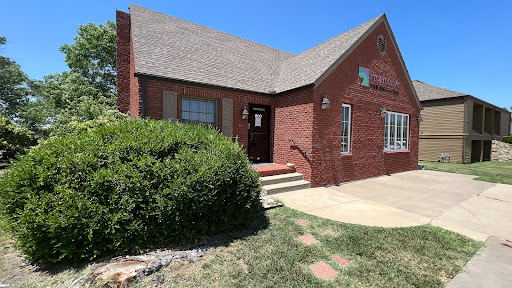 A charming brick house with a neatly maintained front yard under a clear blue sky.
