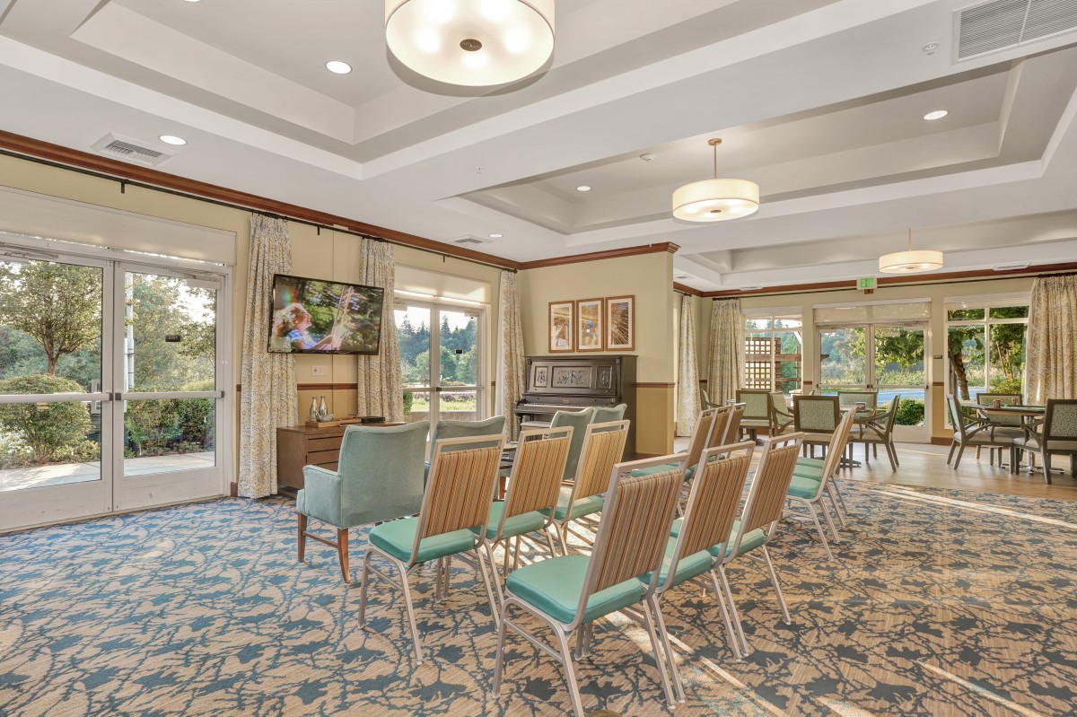 A well-lit conference room with chairs arranged facing a television and large windows.