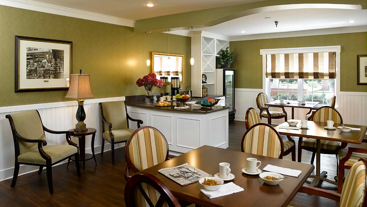 A cozy dining area with a breakfast setup, featuring tables, chairs, and a buffet counter.