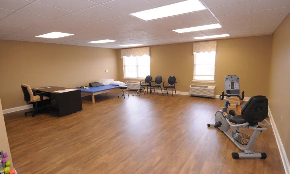 A spacious physical therapy room equipped with exercise machines and seating.