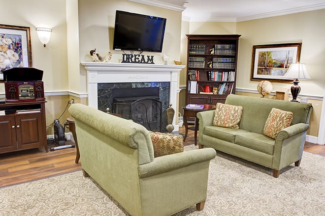 A cozy living room with comfortable sofas, a fireplace, and a bookshelf.