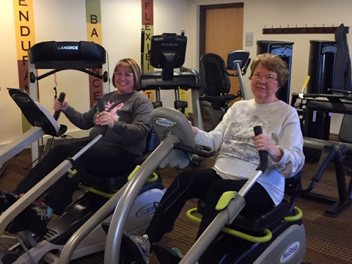 Two women enjoying a workout on elliptical machines in a gym.
