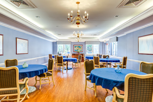 A spacious dining room featuring blue tablecloths and elegant lighting.