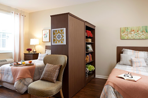 A stylishly designed bedroom featuring a shared space with a bookshelf divider, cozy beds, and soft lighting.