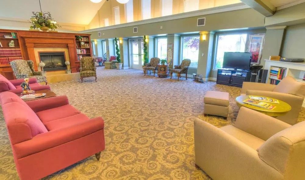 A spacious and bright lobby with comfortable seating, large windows, and a television, designed for relaxation.