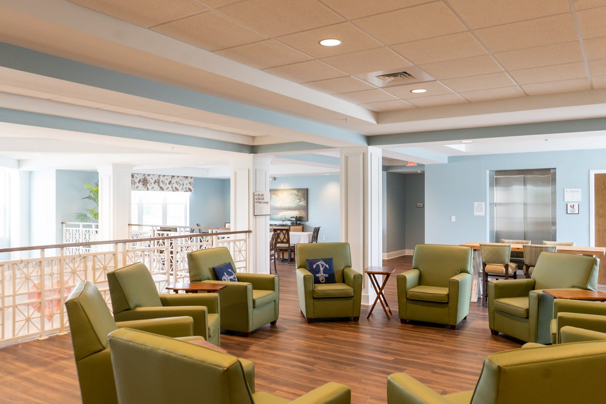A modern, inviting living room with green armchairs arranged in a circle.
