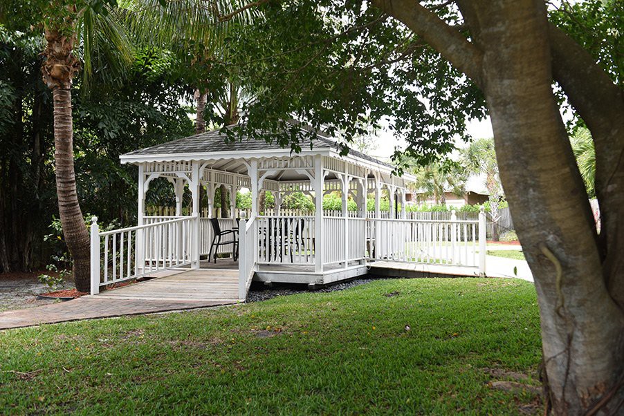 A white gazebo surrounded by trees and grass in a park setting.