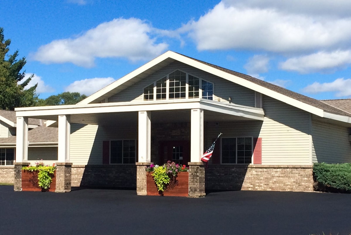 A suburban house with a gabled roof and columns under a blue sky.