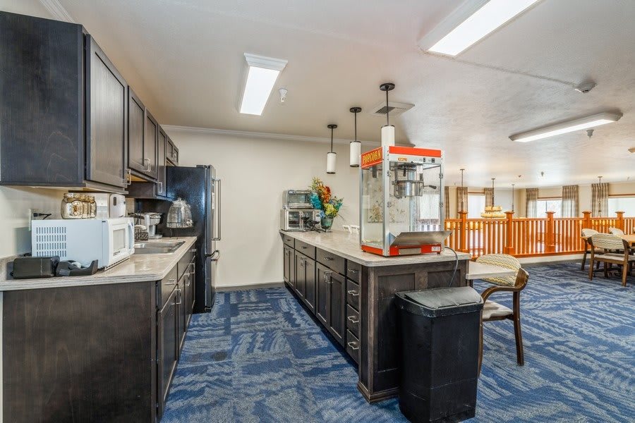 A modern kitchen interior featuring a popcorn machine on the countertop with seating stools and various appliances.