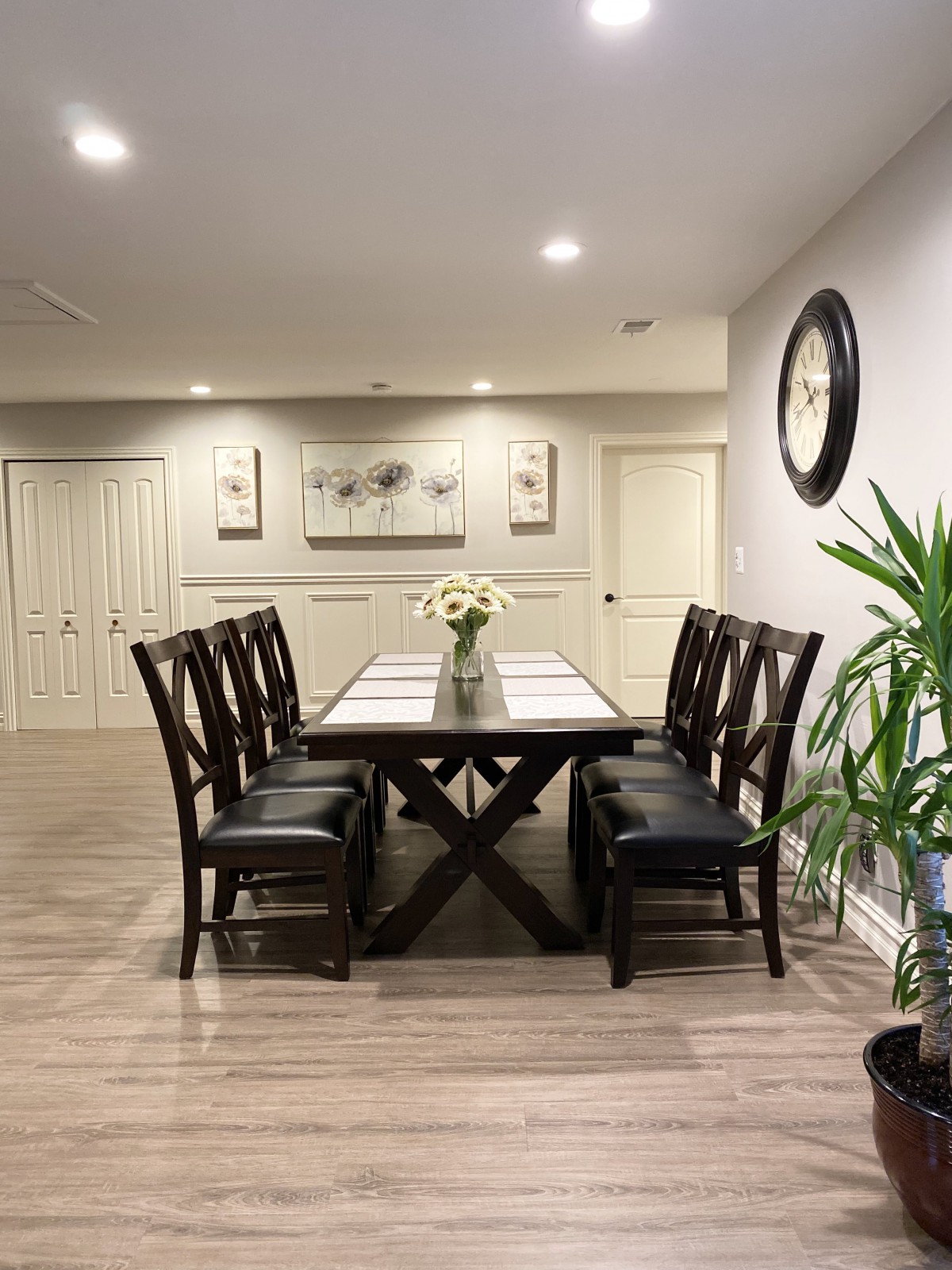 A modern dining room with a long table, six chairs, and minimalistic decor.