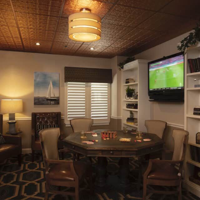 A cozy living room with a round table, chairs, and a TV on the wall.