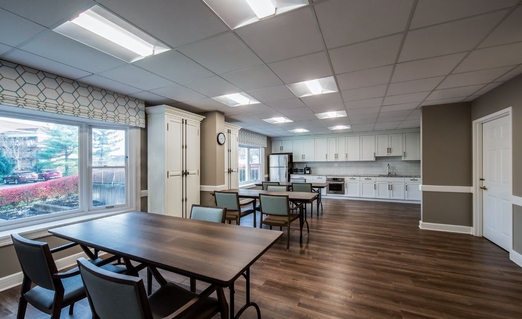 A modern kitchen and dining area featuring tables, chairs, appliances, and hardwood flooring.