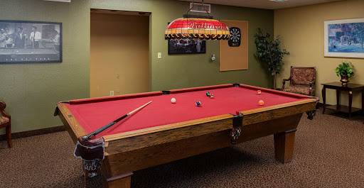 A well-lit pool table set up for a game in a cozy game room.