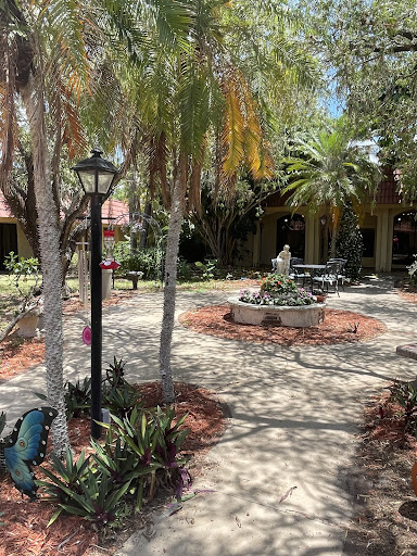 A serene garden pathway with a fountain surrounded by palm trees and well-maintained landscaping.