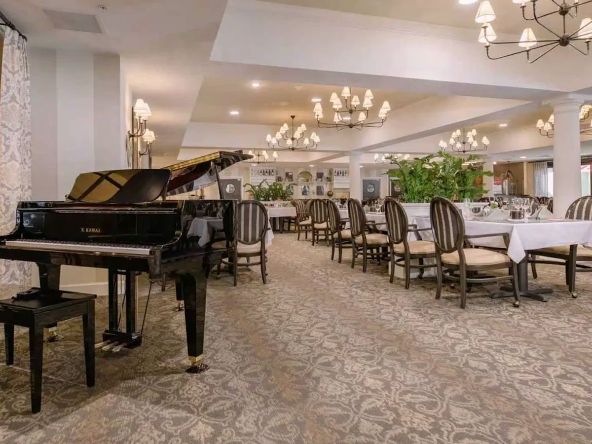 An elegant restaurant interior with a grand piano and stylish dining furniture.