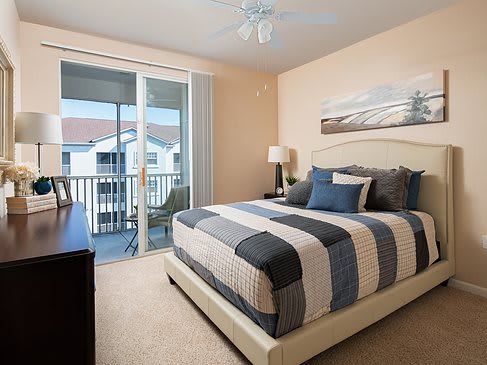 A cozy bedroom with a king-sized bed, stylish decor, and sliding doors leading to a balcony.