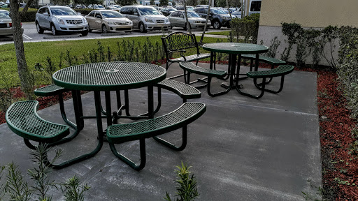A set of green outdoor tables and benches arranged in a casual seating area.