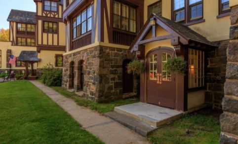 A charming building entrance with stone accents and manicured greenery along the pathway.