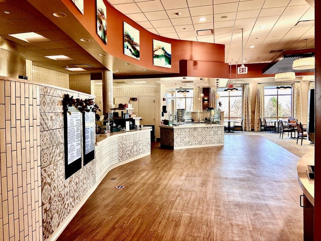 A modern and spacious cafe interior with a wooden floor and stylish counter.