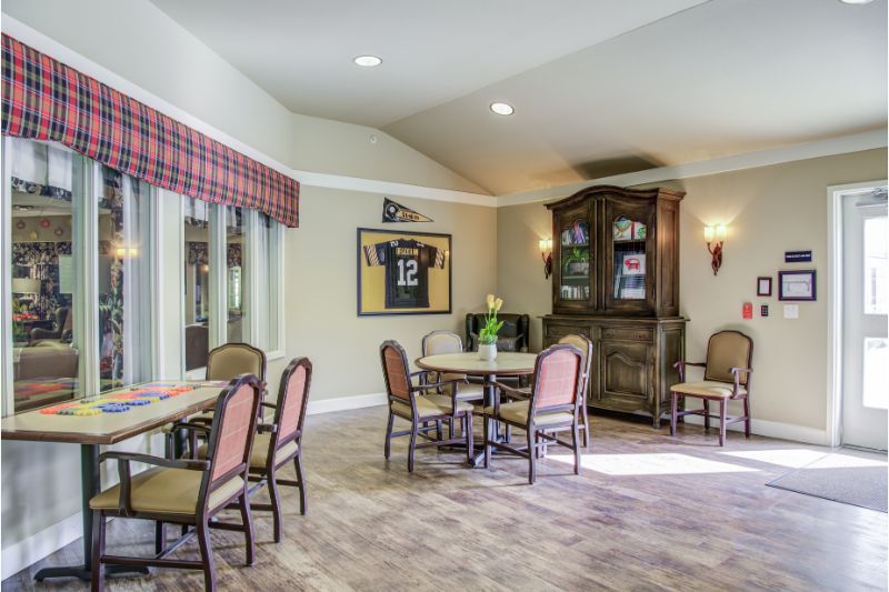 A cozy dining space with tables, chairs, and a framed jersey on the wall.
