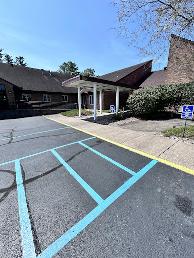 A view of the entrance to a building, featuring a well-defined parking area with accessible spots.