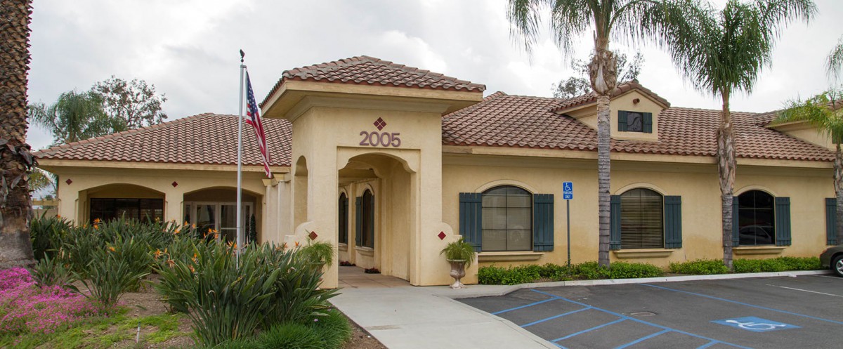 A beige building with an archway entrance, displaying the number 2006 and an American flag nearby.
