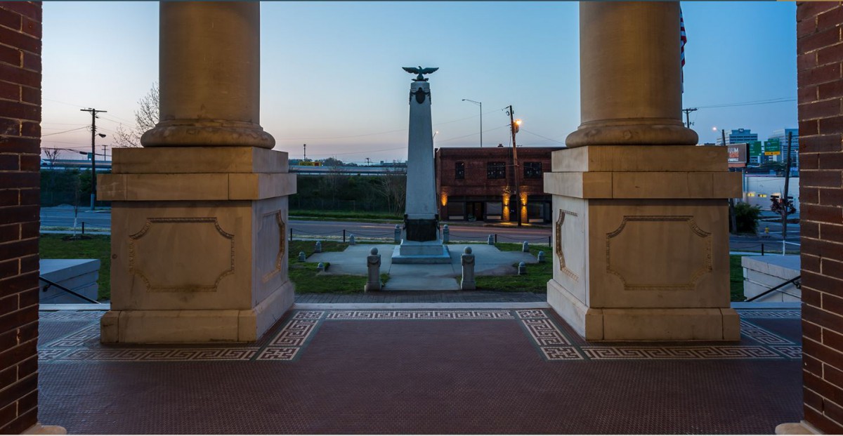 A view of a monument framed by architectural columns during sunset.