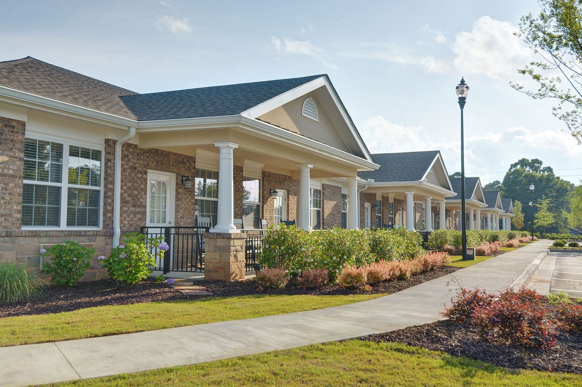 A row of suburban houses with front porches and landscaped yards on a sunny day.