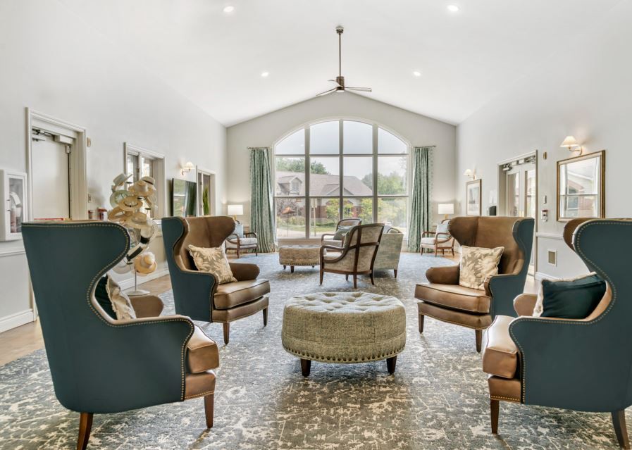 A spacious, elegantly designed living room featuring armchairs and a large window with natural light.