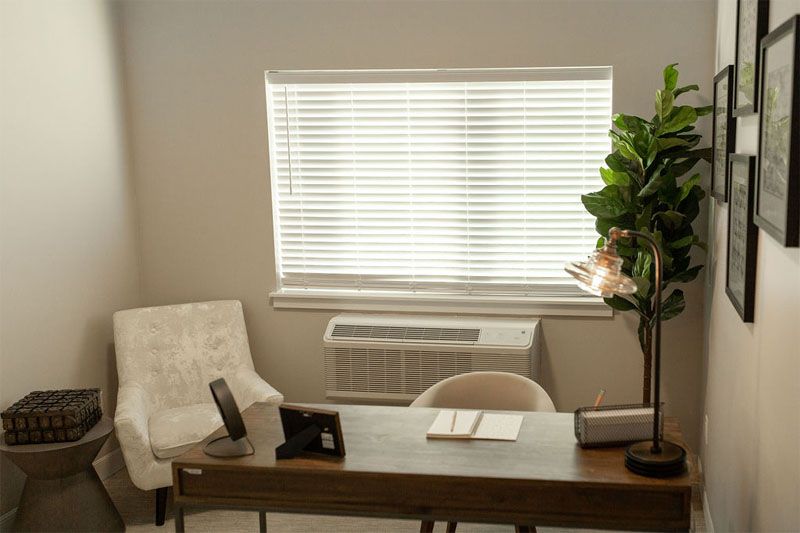 A tidy office space with a desk, chair, and window blinds.