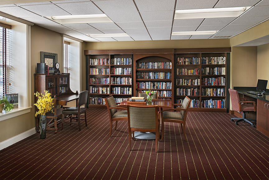 A cozy library reading room with bookshelves, a table, and chairs.