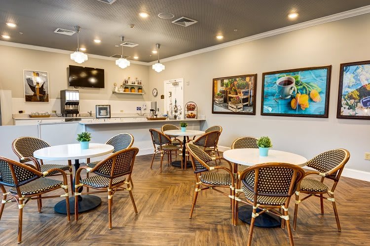 A cozy cafe interior with tables, chairs, and decorative artwork.