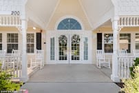 A welcoming front porch with double doors, rocking chairs, and an arched window.