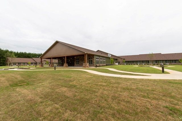 A wooden building with a sloped roof surrounded by grassy areas and pathways.