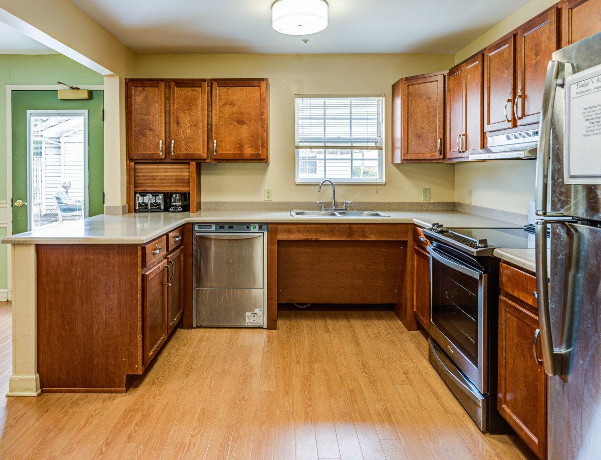 A modern kitchen with wooden cabinets, stainless steel appliances, and hardwood flooring.