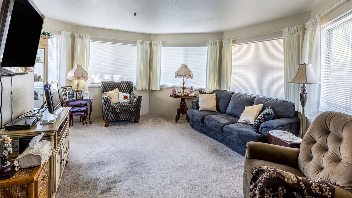 A cozy living room with a blue sofa, patterned armchair, and table lamps by the windows.