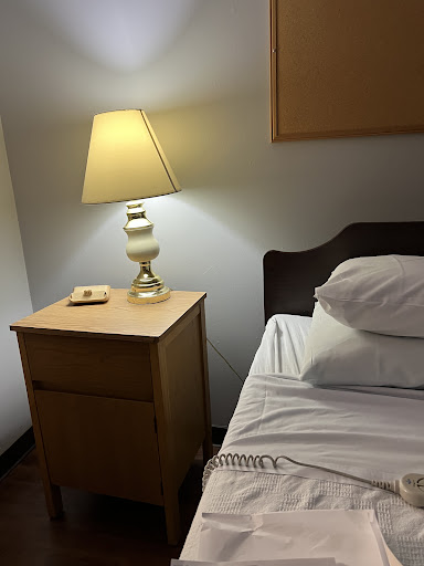 A cozy bedroom setup featuring a nightstand with a lamp beside an unmade bed.
