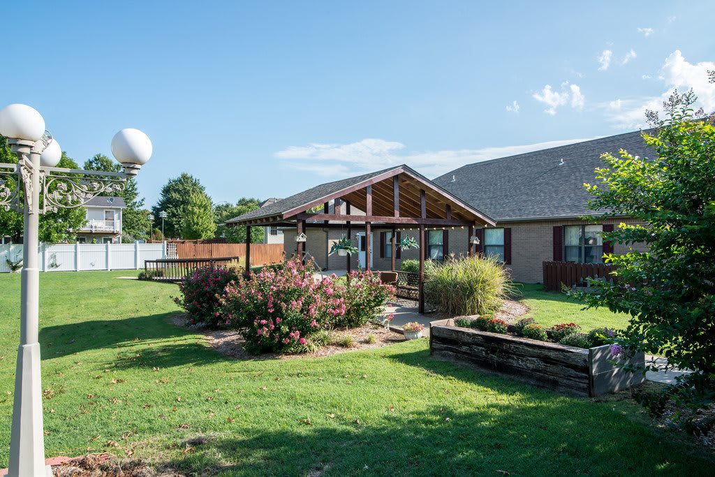 A well-maintained backyard with a patio and landscaped garden, featuring a lawn and various plants.