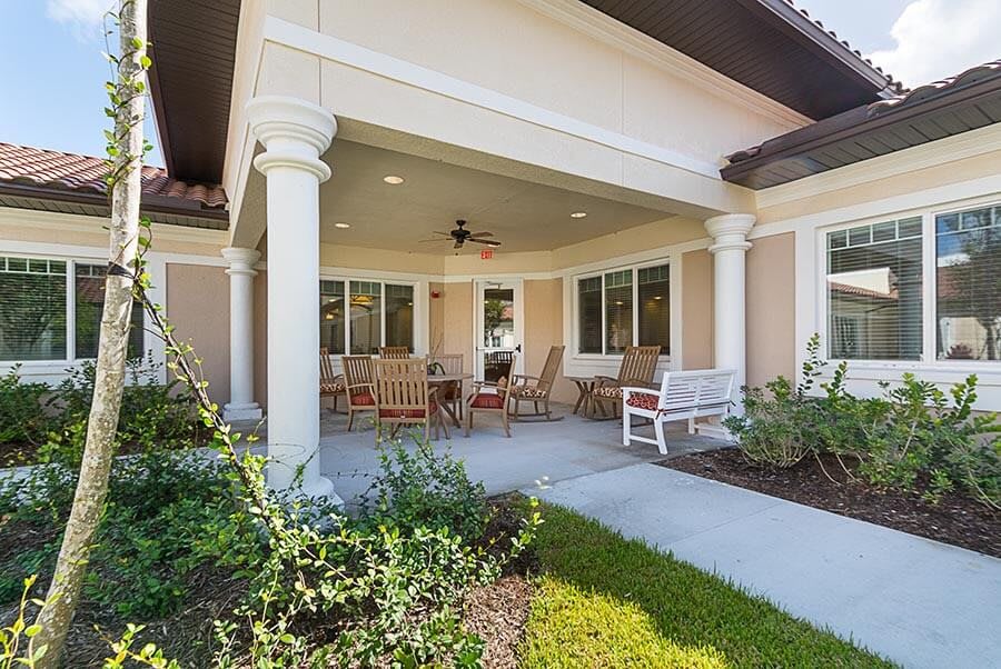 A cozy covered patio with outdoor seating and landscaping.