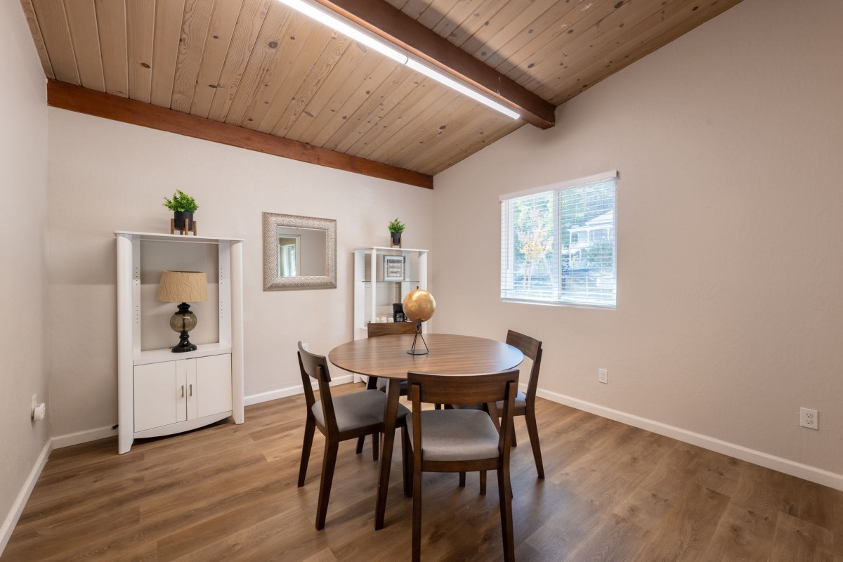 A minimalist dining room with a round table and wooden ceiling.
