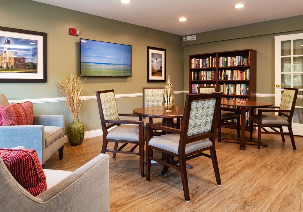 Cozy reading room with a bookshelf, table, and chairs.