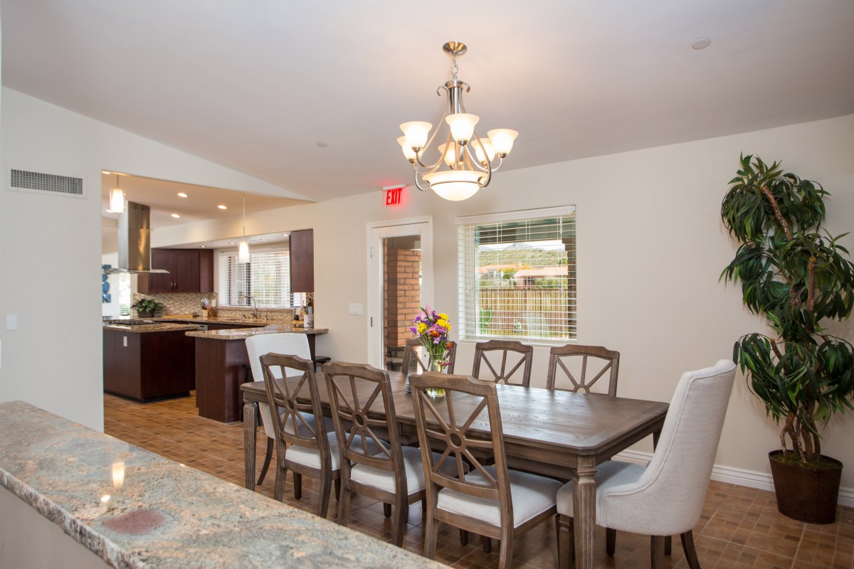 A spacious dining area connected to a modern kitchen, featuring a large table with chairs and elegant lighting.