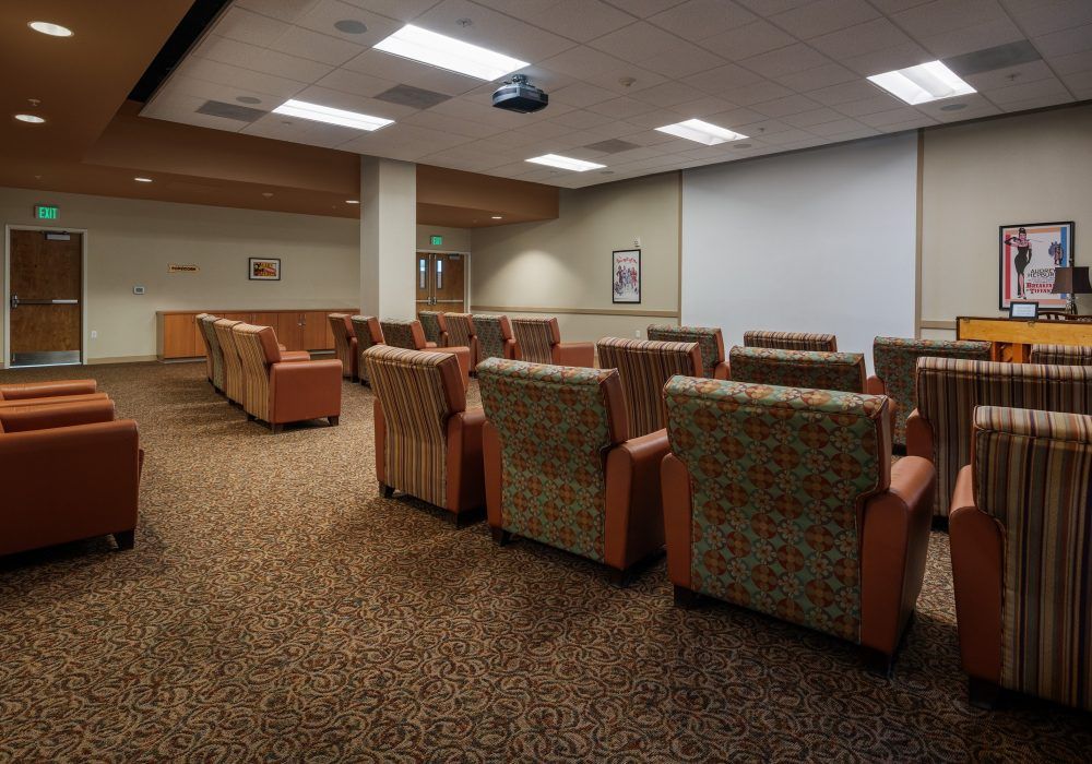A comfortable seating area with plush chairs facing a projector screen, suitable for meetings or presentations.