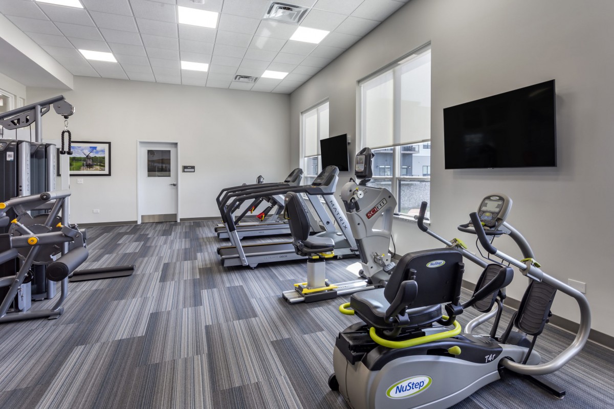 A modern gym with treadmills and a stationary bike in a well-lit room.