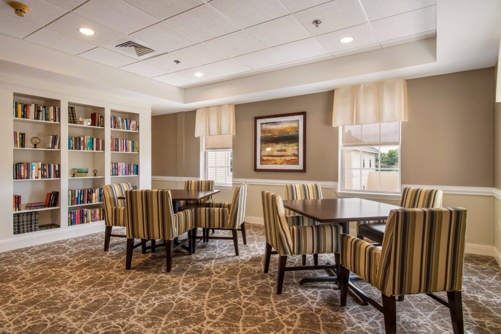 A cozy meeting room with bookshelves and tables surrounded by striped chairs, ideal for reading or discussions.