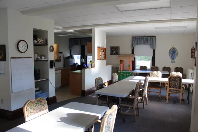 A community dining area with tables and chairs, connected to a kitchen space.