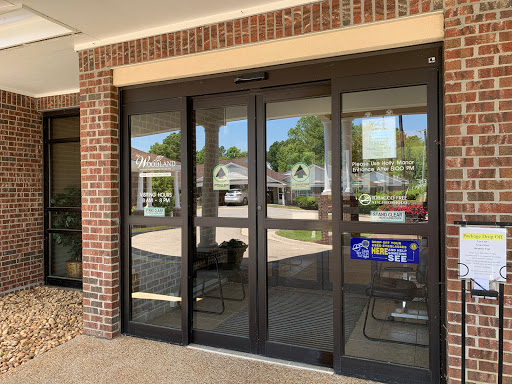 The entrance of a commercial building featuring glass doors with a brick facade.