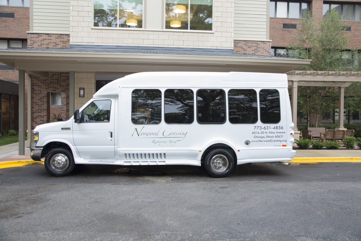 A white shuttle van parked outside a building.
