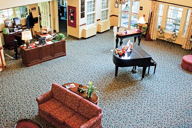 A spacious lobby with a grand piano, upholstered sofa, and elegant furnishings.