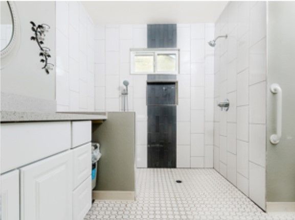 A modern, minimalist bathroom with white tiles and a spacious shower area.